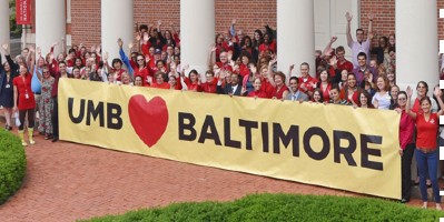 UMB students gathered around a banner that reads 'UMB loves Baltimore'