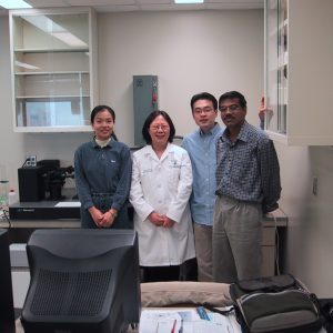Dr. Lowe in a lab coat with lab members