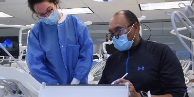 An instructor demonstrates dental techniques for a student in the simulation lab