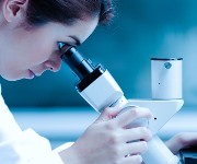 A dental professional looks through a microscope