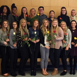 A group of dental hygiene students holding roses