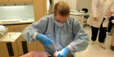 A dental hygiene student performing a cleaning