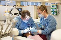 Two students perform a dental procedure