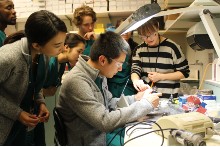 An instructor demonstrates dental techniques for three students