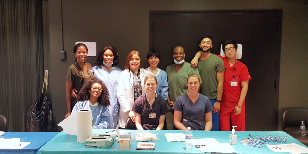 Dr. Melo poses with members of the American Student Dental Association at a Lexington Market dental screening event