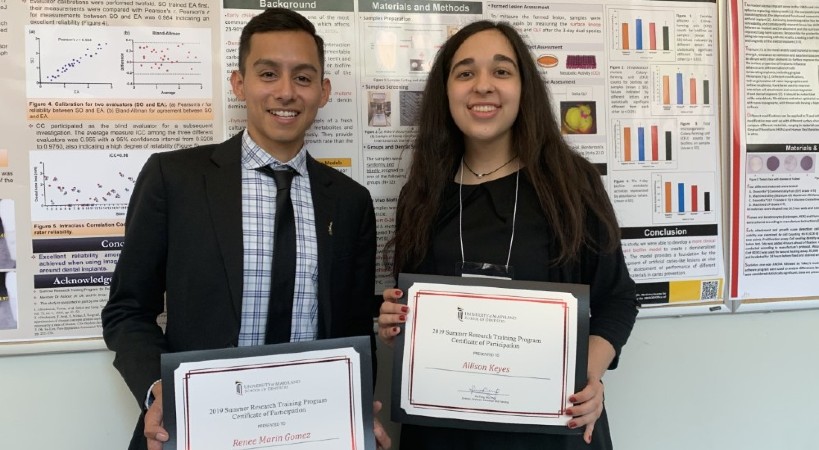 Two students display certificates