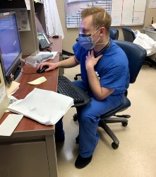 A doctor works at his desk while wearing a face mask