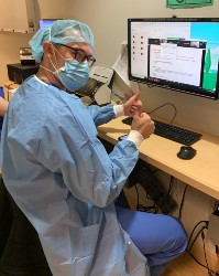 A doctor works at his desk while wearing personal protective equipment