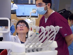 An instructor guides a dental student in the simulation lab