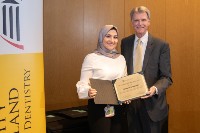 A student and two instructors pose with an award