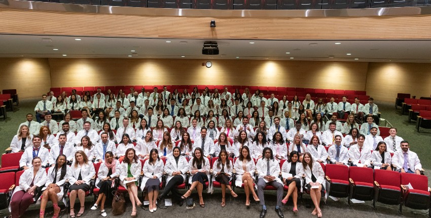 A group of graduates pose in white coats