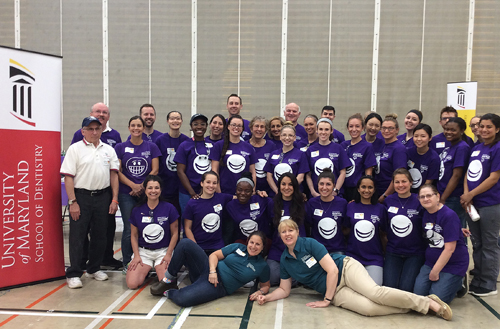 Professor Emeritus Mark Wagner, DMD, second row, left, is among volunteers at the 2017 Special Smiles clinic during Special Olympics Maryland at Towson University. In the foreground, left to right, are organizers Leila Liberman, RDH, MDE, clinical instructor, and Sheryl Syme, RDH, MS, associate professor, University of Maryland School of Dentistry. 