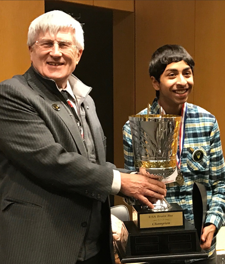 Brain Bee founder Norbert Myslinski, PhD, associate professor at the University of Maryland School of Dentistry, presents a trophy to 2017 USA champion Sojas Wagle of Little Rock, Ark.